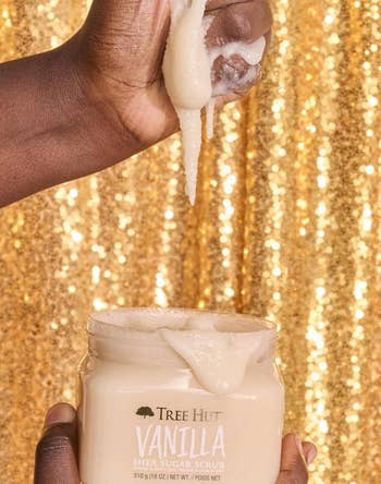 Person holding and scooping vanilla shea scrub