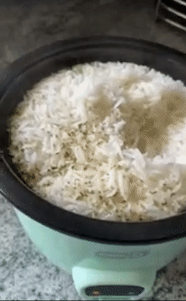 reviewer spooning cooked rice out of the aqua blue version