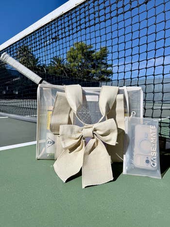 Clear tote container  with a ample  bow, placed connected  a tennis court. Includes a CASE-MATE telephone  lawsuit  with dual camera cutouts and a tennis shot  inside