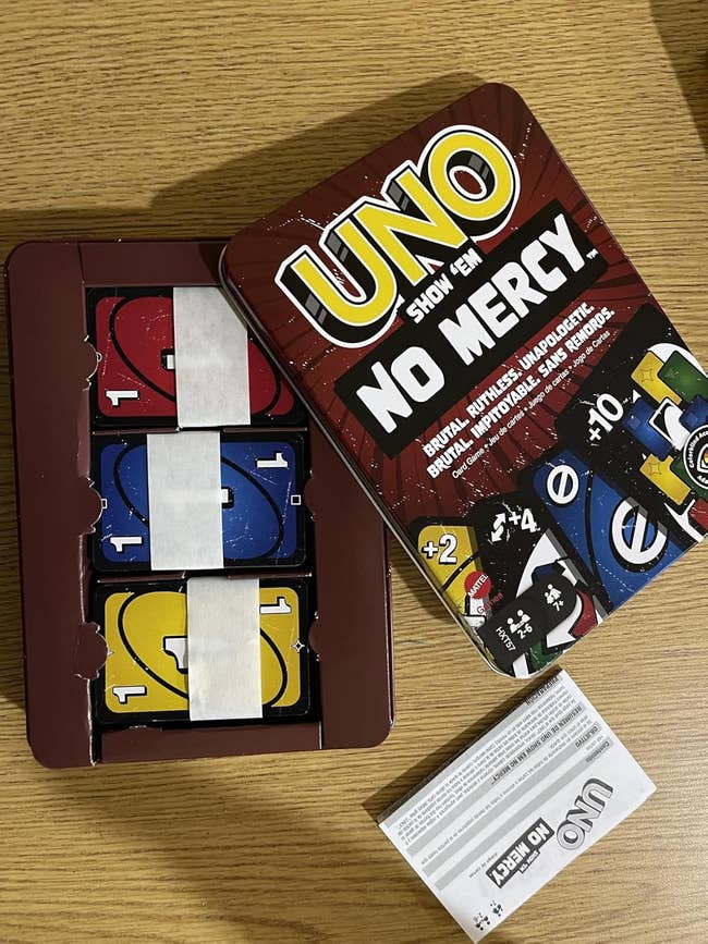 UNO Show 'Em No Mercy paper crippled connected a array with cards successful a tray and regularisation booklet