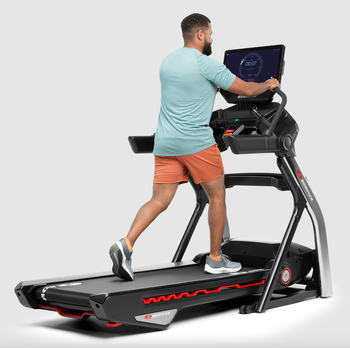 man running on Bowflex treadmill, holding onto handlebars