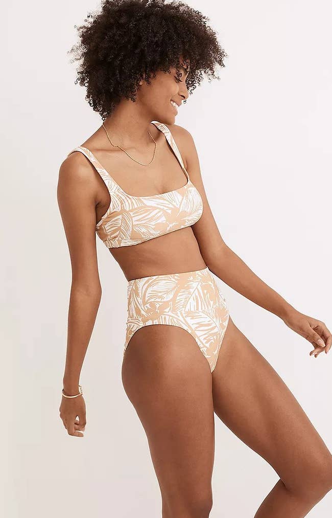 a model wearing a tan balconette top with high-waisted bottoms featuring a tan and white palm print 