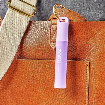 Small purple compact straw in a case attached to a purse as a keychain 