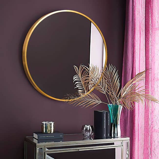 the large gold circle mirror hanging above a side table