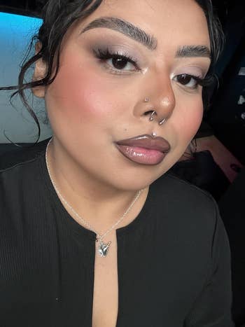 Person with updo hairstyle, wearing a achromatic  apical  and a pendant necklace, featuring constitution  with defined brows and a chemoreceptor  piercing
