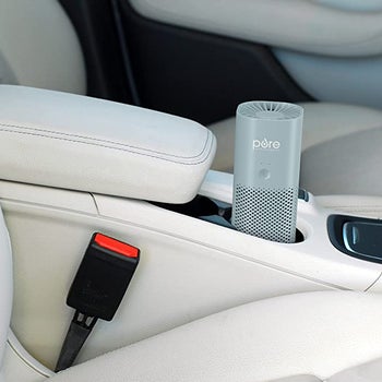 a mini blue air purifier in the cupholder of a car