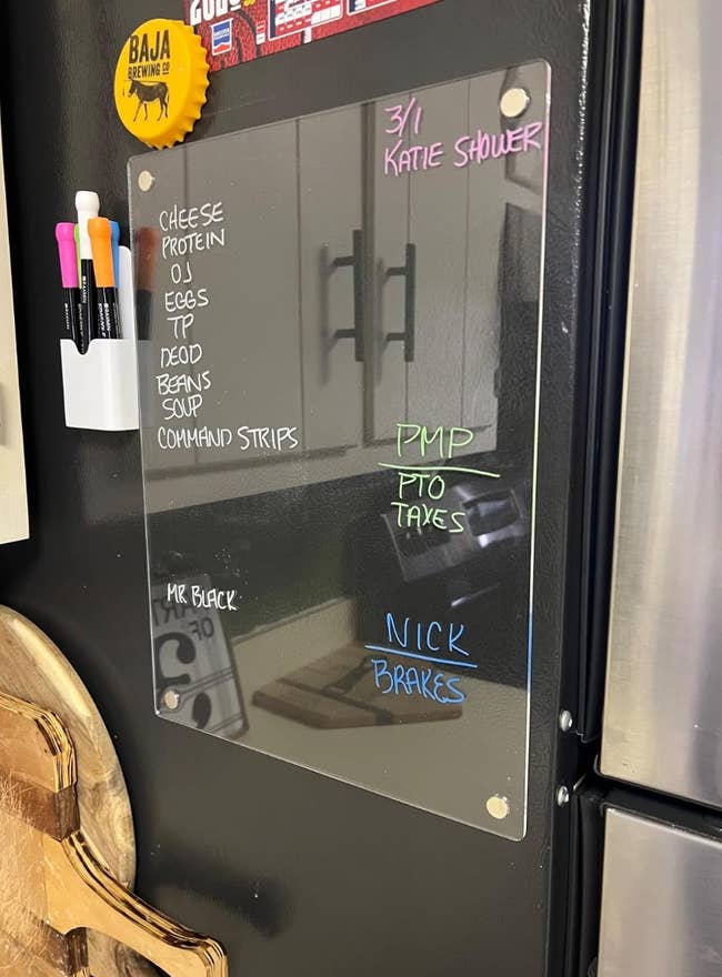 A fridge with a clear board listing household items like cheese, protein, eggs, and reminders such as 