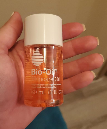 eco travel size toiletries reviewer holding mini bottle of bio oil