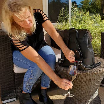 A model pouring red wine into a glass from the backpack