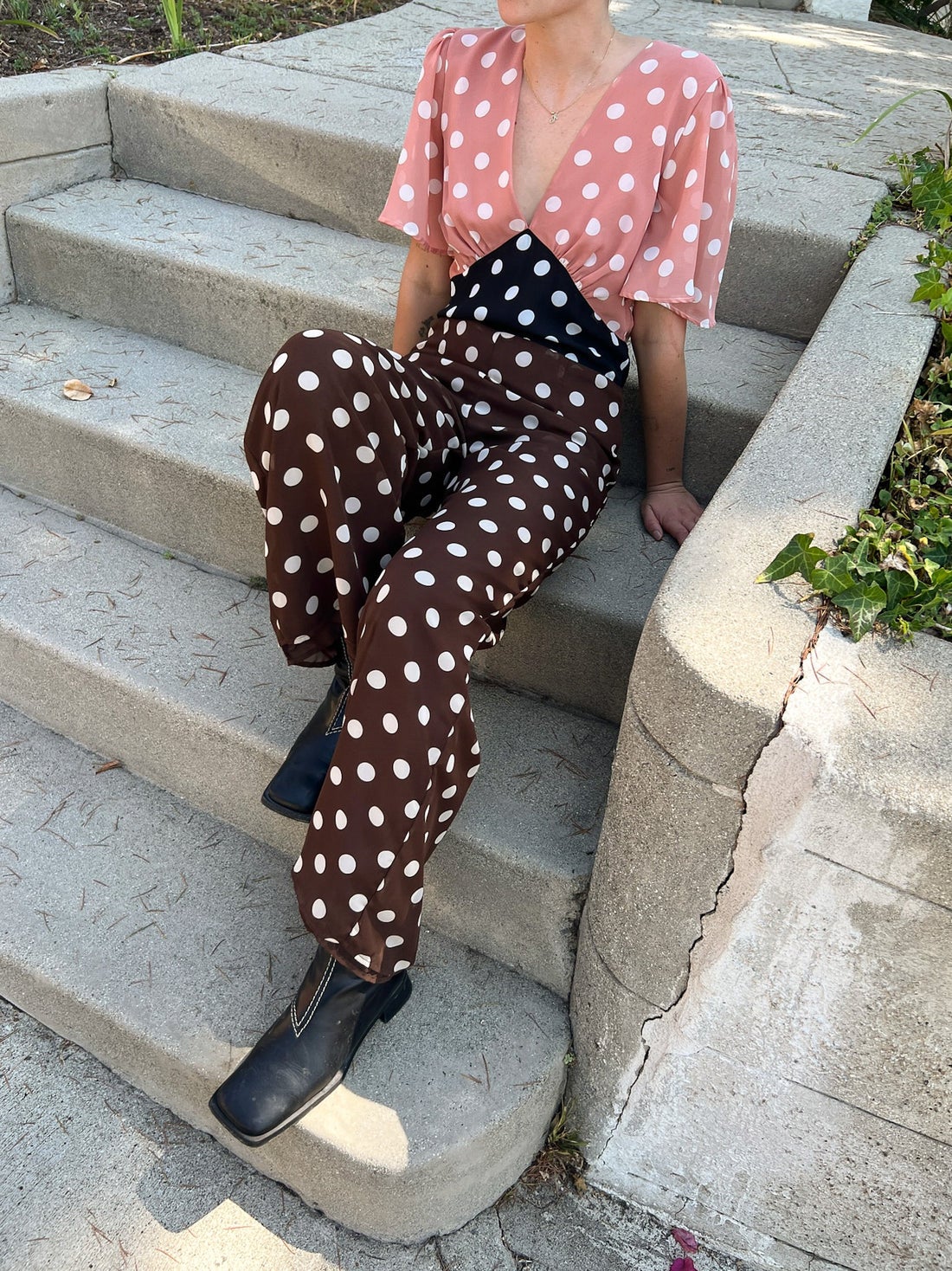 a model sitting in the pink, black, and brown jumpsuit