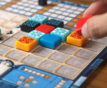 a model placing printed tiles on a game board 