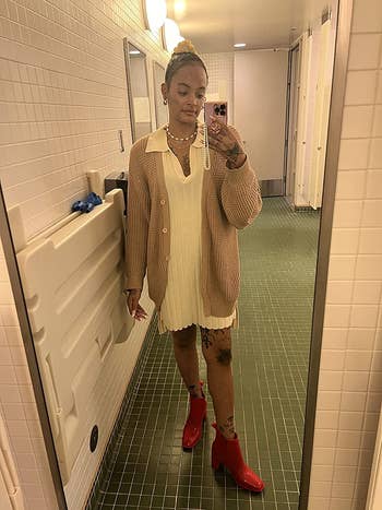 reviewer photo of them wearing a beige cardigan over a white dress with red boots
