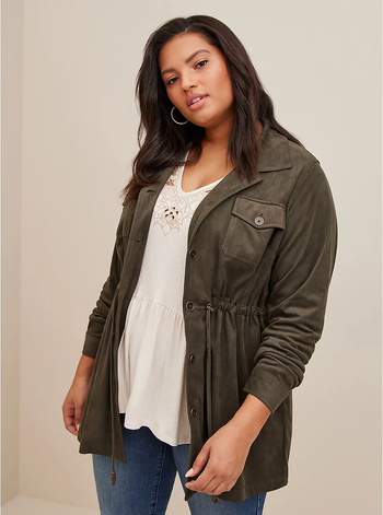 front of a model wearing an olive suede shacket over a white tee and blue jeans