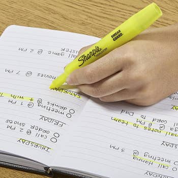 hand using a yellow highlighter in a notebook 