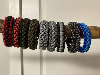 Nine braided bracelets successful assorted patterns and textures bent connected a woody rod
