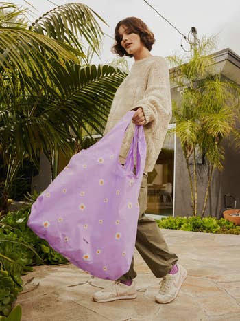 model carrying the purple tote with small white flowers on it