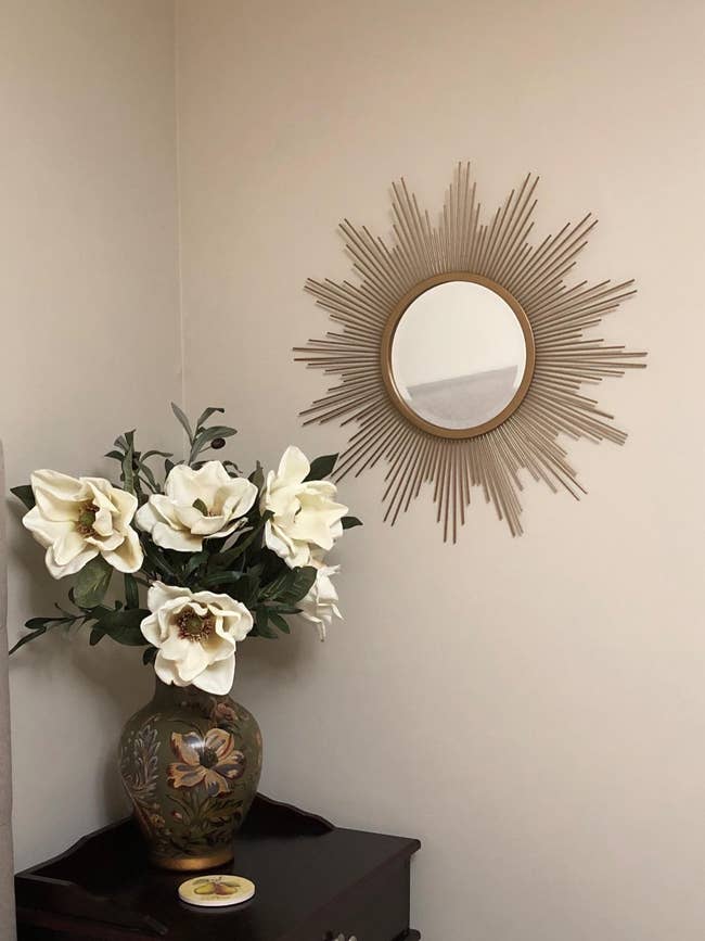reviewer image of the gold sun-shaped mirror hanging on a wall