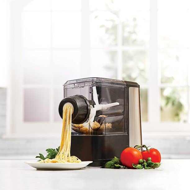 A pasta machine with fresh pasta coming out of it