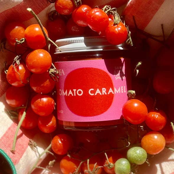 Jar of tomato caramel sauce surrounded by fresh cherry tomatoes