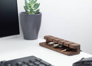A wooden desktop organizer holds various cables next to a computer