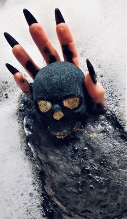 hand holds skull bath bomb in water