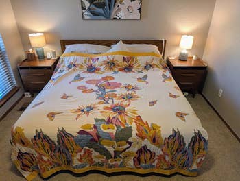 A neatly made furniture with a floral-patterned quilt, flanked by 2 nightstands with lamps, suggesting a cozy and inviting chamber setting