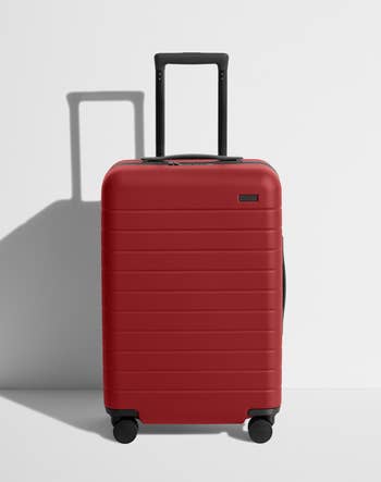 A red hard-shell carry-on suitcase with an extended handle and four wheels