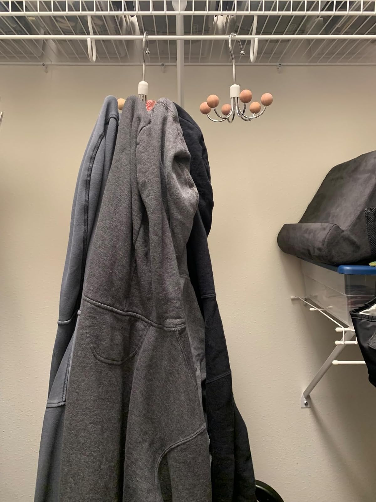 Hoodies digantung di lemari di rak berkabel, dengan tempat penyimpanan di dekatnya