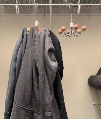 Hoodies digantung di lemari di rak berkabel, dengan tempat penyimpanan di dekatnya