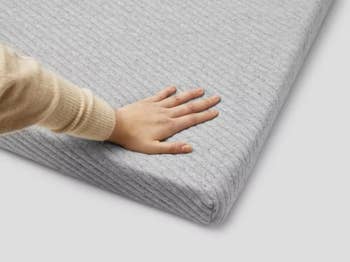 hand pressing into the foamy mattress topper