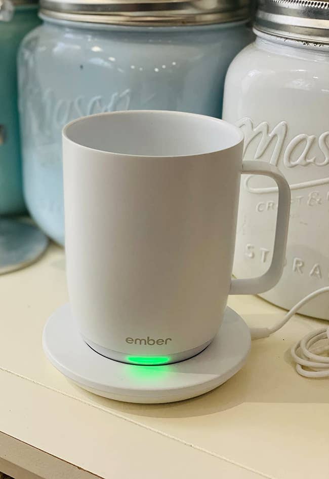A reviewer's temperature control mug plugged in with the indicator light on