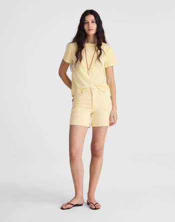 Person wearing a casual yellowish t-shirt with matching shorts, a reddish necklace, and flip-flops. Ideal for summertime casual wear