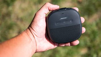 reviewer holding black bose speaker outdoors