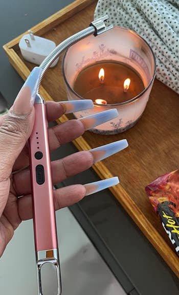reviewer holding the pink lighter in front of a lit candle