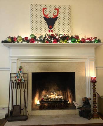 reviewer photo of the lit candle holder in their fireplace