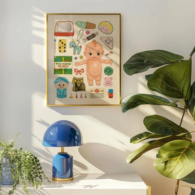 Framed poster connected a partition featuring vintage-style illustrations of a doll, toys, and assorted objects. Blue lamp and works nearby