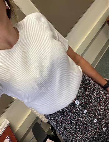 Person in a textured white top and embellished skirt