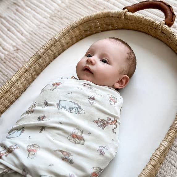 Baby wrapped successful a patterned swaddle, lying successful a wicker bassinet