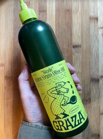 BuzzFeed writer Ross Yoder holding green and yellow bottle of the Graza Sizzle Olive Oil