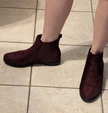 a reviewer wearing burgundy suede chelsea boots with elastic side gores 