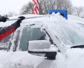 model using the broom to remove snow from car