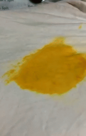 reviewer gif showing the stain remover getting rid of a big orange stain on white fabric