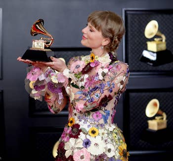 photo of taylor swift at the 2021 grammy awards wearing the floral dressing and holding a grammy