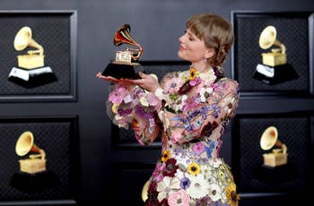photo of taylor swift at the 2021 grammy awards wearing the floral dressing and holding a grammy