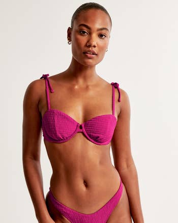 Model posing in a textured magenta bikini