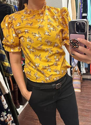a reviewer wearing the shirt in yellow featuring a white floral print 