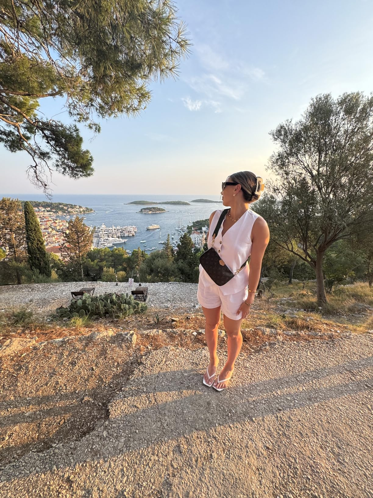 Person successful  a achromatic  outfit with a crossbody container  stands connected  a scenic place  with a coastal presumption    successful  the background