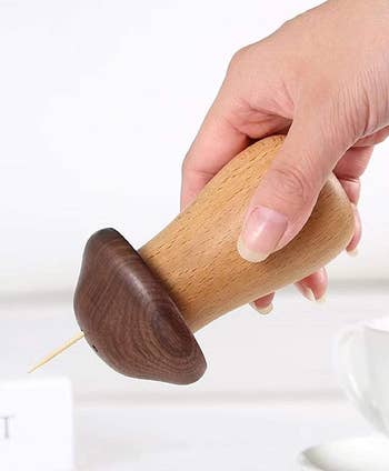 A reviewer tilting a mushroom to dispense a toothpick 
