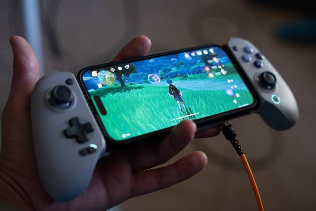 A hand holding a smartphone with a game controller attached