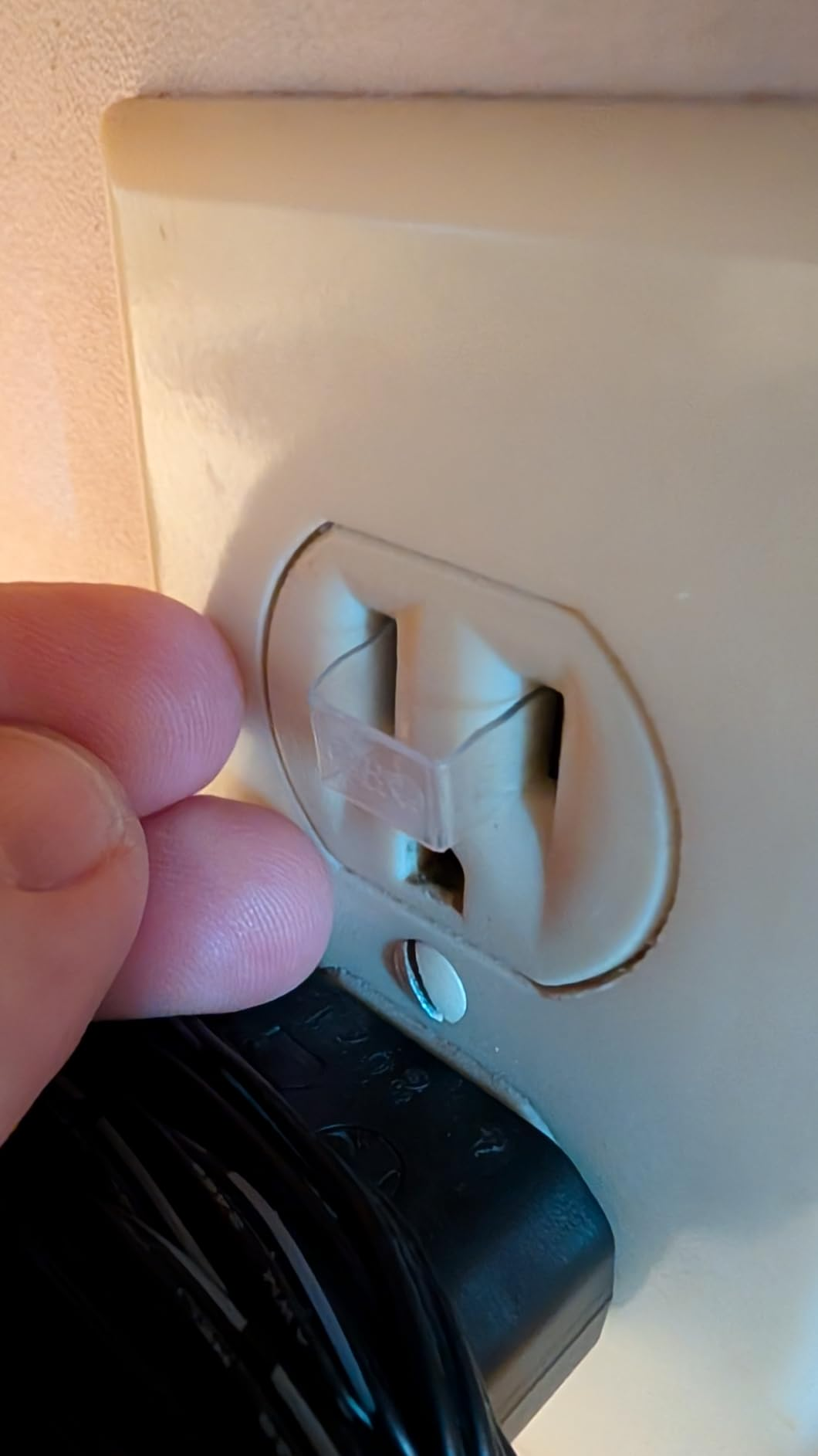 Fingers pressing a information   screen  into an electrical outlet, with a achromatic  plug partially disposable   below